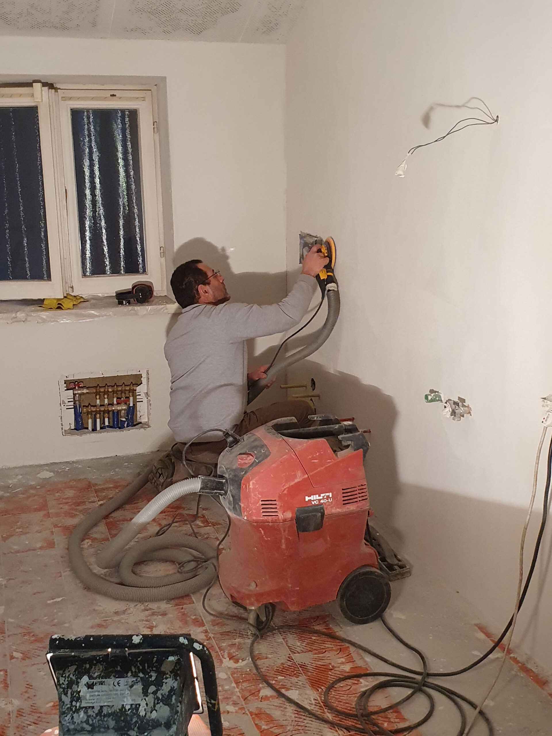 Applicazione del microcemento Microtopping®, levigatura dopo la prima stesura su vecchie piastrelle a parete